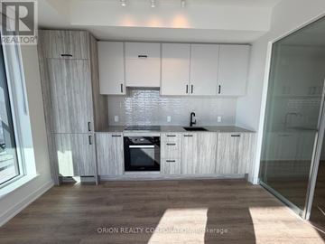 Toronto (Banbury-Don Mills) condo for rent - A modern kitchen with white cabinets and a wooden floor.