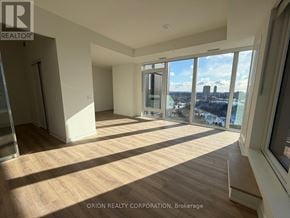 Toronto (Banbury-Don Mills) condo for rent - A large, empty room with wooden floors and a view of the city through large windows.
