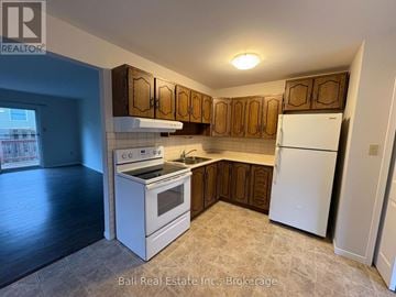 Kawartha Lakes (Bobcaygeon) multi-family for rent - A kitchen with white appliances and wooden cabinets.
