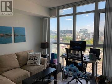 Toronto (Waterfront Communities) condo for rent - A living room with a couch, a chair, and a table with a lamp on it.