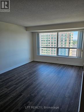 Toronto (Woburn) condo for rent - A room with wooden flooring and a large window overlooking a cityscape.
