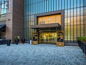 Toronto (Waterfront Communities) condo for rent - The entrance to a building with a glass facade and a brick column.