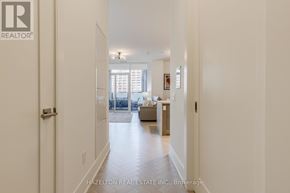 Toronto (Waterfront Communities) condo for rent - A hallway with a door on the left and a living room with a couch and a coffee table on the right.