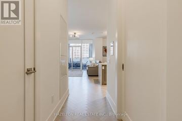 Toronto (Waterfront Communities) condo for rent - A hallway with a door on the left and a living room with a couch and a coffee table on the right.