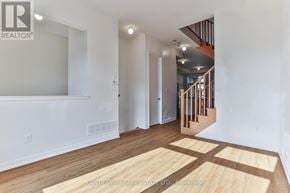 Markham (Wismer) townhouse for rent - A spacious room with wooden flooring and a staircase in the background.