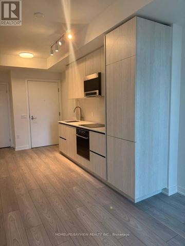 Toronto (Mount Pleasant West) condo for rent - A modern kitchen with wooden cabinets and a white door.