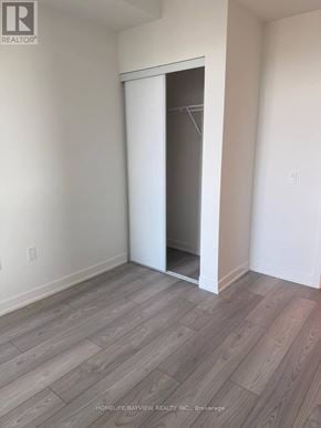 Toronto (Mount Pleasant West) condo for rent - A room with a white wall and a wooden floor with a door open.