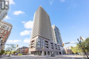 Burlington (Brant) condo for rent - A tall building with a curved facade stands in the middle of a city intersection.