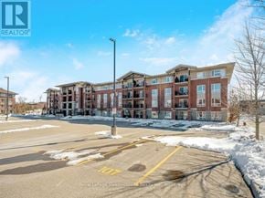 Guelph (Pineridge/Westminster Woods) condo for rent - A large building with a parking lot in front of it.