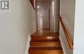 Brampton (Bram East) apartment for rent - A hallway with wooden stairs leading to a door at the end.