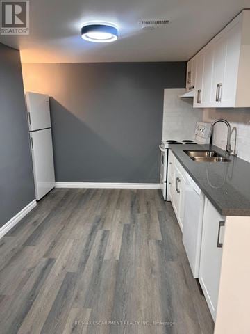 Brantford apartment for rent - A kitchen with white cabinets and a grey floor.