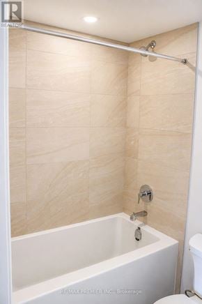 Mississauga (City Centre) condo for rent - A white bathtub with a shower head and a toilet in a bathroom.