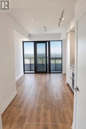 Mississauga (City Centre) condo for rent - A large empty room with wooden floors and a balcony with a view of the city.