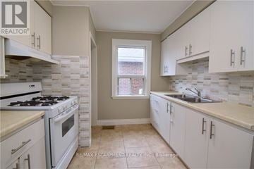 Hamilton (Delta) apartment for rent - A kitchen with white cabinets and a tiled backsplash.