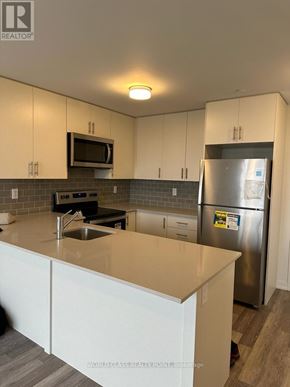 Mississauga (Erin Mills) condo for rent - A kitchen with a stainless steel refrigerator and a microwave above the stove.