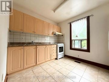 Toronto (South Riverdale) townhouse for rent - A kitchen with wooden cabinets and a tiled backsplash.
