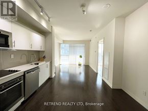 Toronto (Moss Park) condo for rent - A spacious kitchen with white cabinets and black appliances.