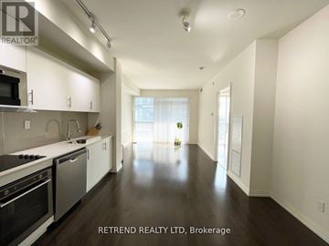 Toronto (Moss Park) condo for rent - A spacious kitchen with white cabinets and black appliances.
