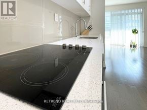 Toronto (Moss Park) condo for rent - A modern kitchen with a black stove top and white countertops.
