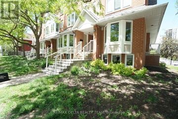 Ottawa townhouse for rent - A house with a red brick facade and white trim is shown with a green lawn in front.