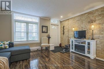 London East (East K) multi-family for rent - A living room with a grey couch, a white chair, a television and a brick wall.