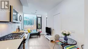 Toronto (Waterfront Communities) condo for rent - A modern kitchen with a stove top oven and a glass table with a vase of flowers on it.