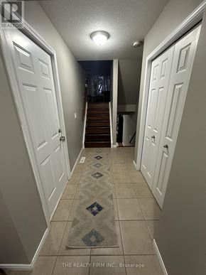 London East (East D) townhouse for rent - A hallway with a rug on the floor and a staircase in the background.