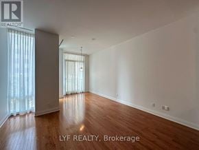 Toronto (Annex) condo for rent - A room with wooden floors and white walls, with a window covered by white curtains.