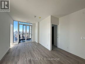 Toronto (Waterfront Communities) condo for rent - A spacious room with wooden flooring and a view of the city through the windows.