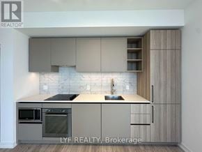 Toronto (Waterfront Communities) condo for rent - A modern kitchen with wooden cabinets and a tiled backsplash.