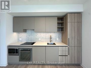 Toronto (Waterfront Communities) condo for rent - A modern kitchen with wooden cabinets and a tiled backsplash.