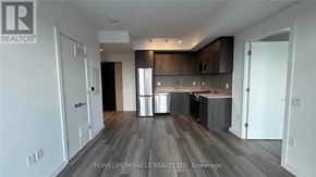 Toronto (Moss Park) condo for rent - A spacious kitchen with dark wood floors and white walls.