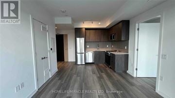 Toronto (Moss Park) condo for rent - A spacious kitchen with dark wood floors and white walls.