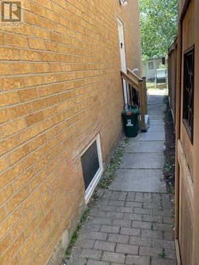 Pickering (Amberlea) apartment for rent - A brick wall with a window and a green trash can.
