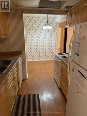 Mississauga (Cooksville) condo for rent - A kitchen with wooden cabinets and a white fridge.