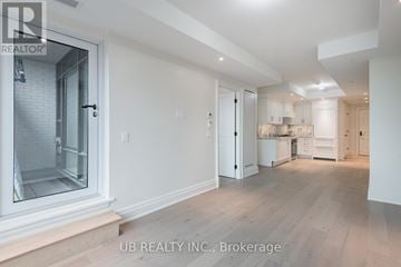 Ottawa condo for rent - A spacious, well-lit room with wooden flooring and white walls, featuring a kitchen area with cabinets and a countertop.