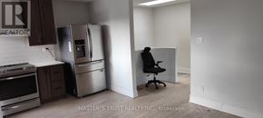 Toronto (Agincourt North) apartment for rent - A man is sitting on a chair in a kitchen with a refrigerator and stove.