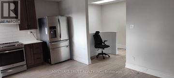 Toronto (Agincourt North) apartment for rent - A man is sitting on a chair in a kitchen with a refrigerator and stove.