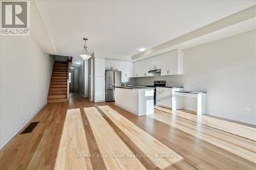 Burlington (Tyandaga) townhouse for rent - A spacious kitchen with white cabinets and a wooden floor.