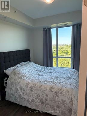 Brampton (Goreway Drive Corridor) condo for rent - A bedroom with a large bed and a view of the countryside through the window.