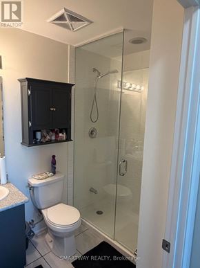 Brampton (Goreway Drive Corridor) condo for rent - A white toilet sits in a bathroom next to a glass shower stall.