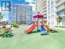Toronto (Wexford-Maryvale) condo for rent - A playground with a red slide and a green lawn in front of apartment buildings.
