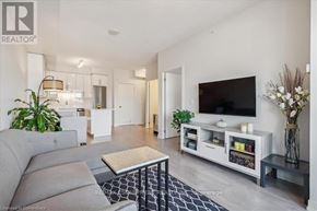 Burlington (Freeman) condo for rent - A living room with a grey sofa and a television on a white stand.