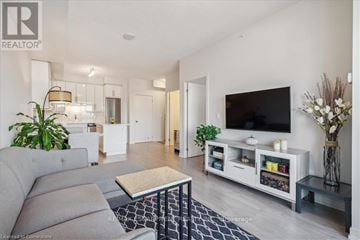 Burlington (Freeman) condo for rent - A living room with a grey sofa and a television on a white stand.