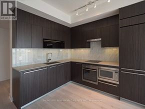 Toronto (Waterfront Communities) condo for rent - A modern kitchen with dark wood cabinets and stainless steel appliances.