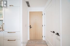 Toronto (Englemount-Lawrence) condo for rent - A white hallway with a wooden door and a black handle.