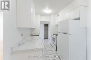 Toronto (Bendale) condo for rent - A white kitchen with a marble counter top and white cabinets.