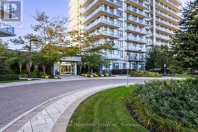 Mississauga (Central Erin Mills) condo for rent - A modern apartment building with a well-maintained lawn and trees in front.