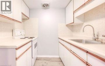 Kitchener townhouse for rent - A small, white kitchen with a sink and a stove.