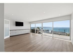 White Rock apartment for rent - A spacious room with wooden floors and a large window overlooking the sea.